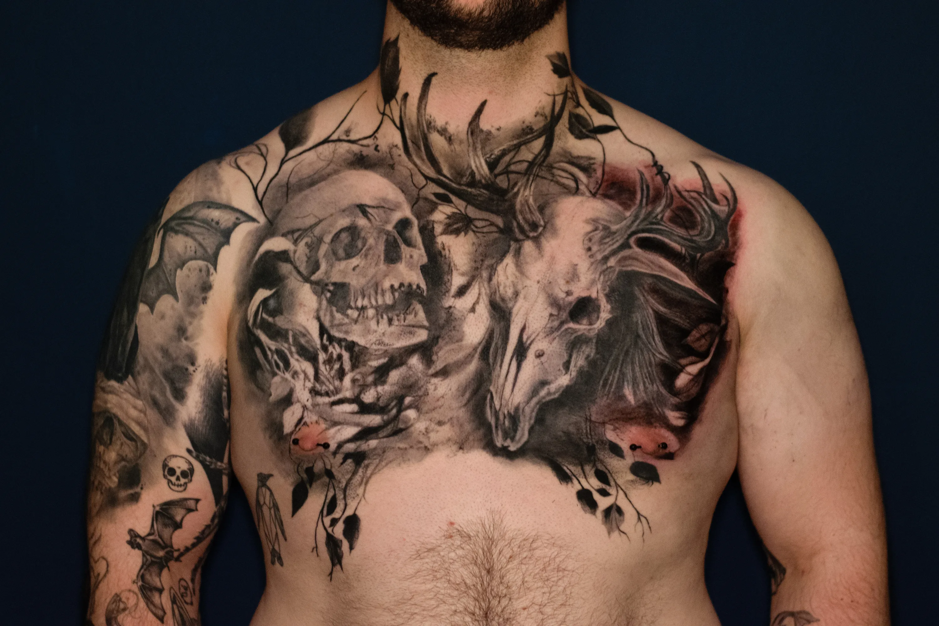 Dark Black-and-Grey-Realismus mit Totenkopf, Tierschädel und abstrakten Ranken auf der Brust